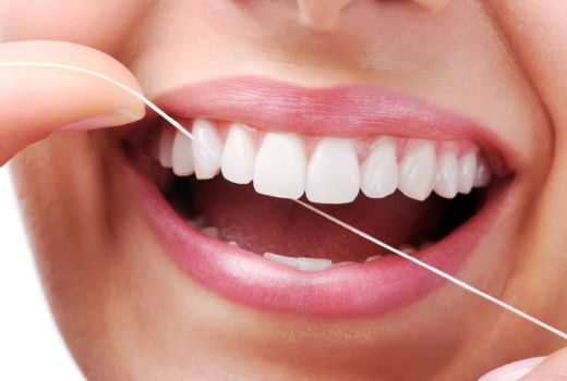 Frau mit weißen Zähnen im gesunden Mund mit Zahnseide im Gebrauch