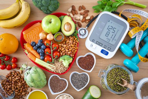 Obst und Gemüse und Nüsse und Blutdruckmessgerät und Stethoskop und Hanteln und Maßband