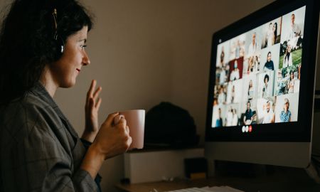Frau sitzt mit Kaffee am Bildschirm vor Onlinefortbildung